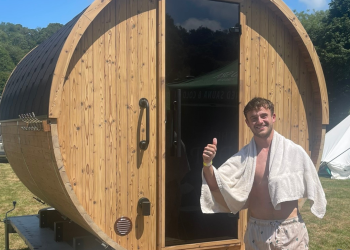 Man giving a thumbs up outside log sauna